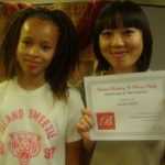 A student who learned how to braid for the first time poses with her model