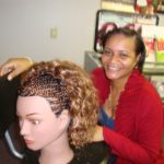 A student at Bukola Braiding Training poses with her mannequin